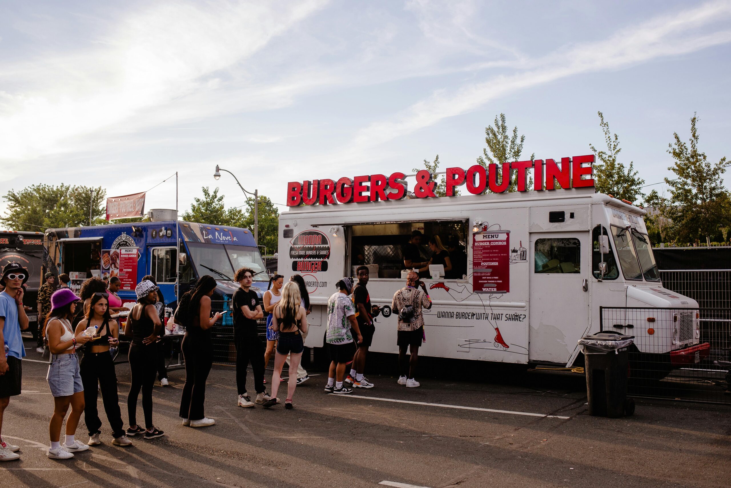 People enjoying food from a burgers and poutine truck in Toronto's urban setting.